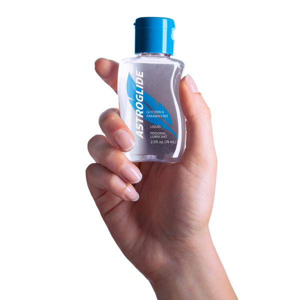 A hand holding a small, clear bottle of Astroglide Glycerin & Paraben Free Liquid Personal Lubricant, 2.5 fl oz, with a blue cap.