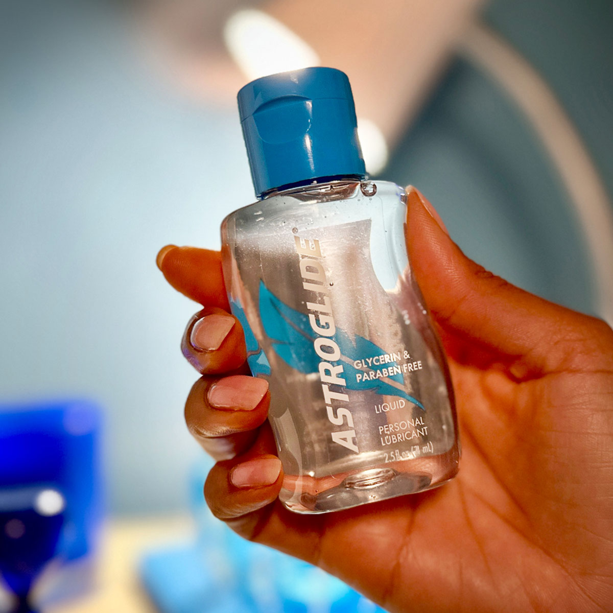 A close-up of a person's hand holding the bottle of Astroglide Glycerin & Paraben Free Liquid Personal Lubricant.