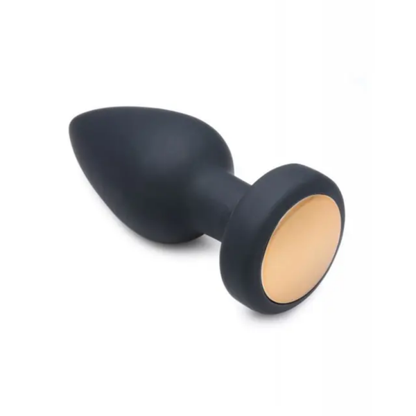 Angled studio view of the black silicone vibrating anal plug lying on its side, detailing the smooth metallic base panel.