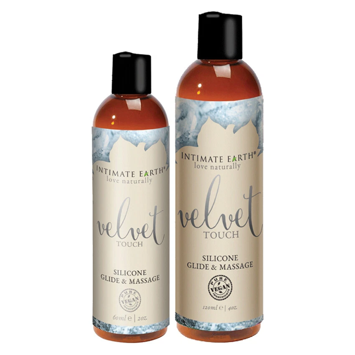 Size comparison view showing two amber bottles of Intimate Earth Velvet Touch silicone glide and massage oil standing side by side in 60 ml (2 fl oz) and 120 ml (4 fl oz) capacities. Imagen principal del producto
