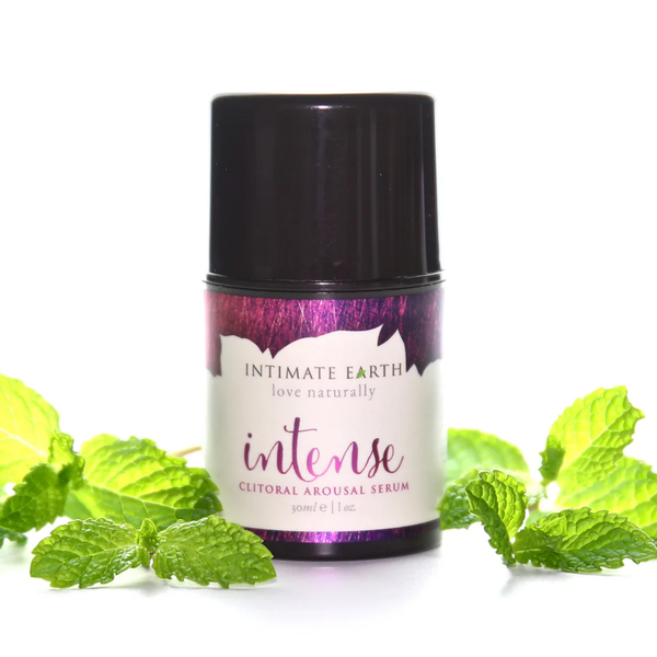 Nature-inspired studio photo showing the 30 ml (1 fl oz) bottle of Intimate Earth Intense clitoral arousal serum surrounded by fresh mint leaves.