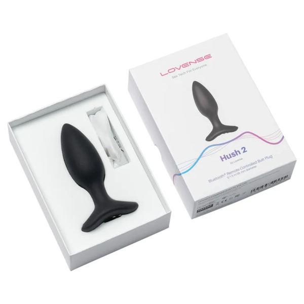 Unboxing perspective photo showing the black 1.5-inch Lovense Hush 2 butt plug resting in the open white box base alongside the charging cable and box lid.