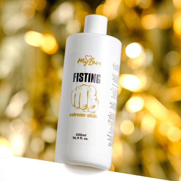 Front view of the 500 ml MyLove Fisting Extreme Slide bottle set against a warm, heavily blurred golden bokeh lighting background.