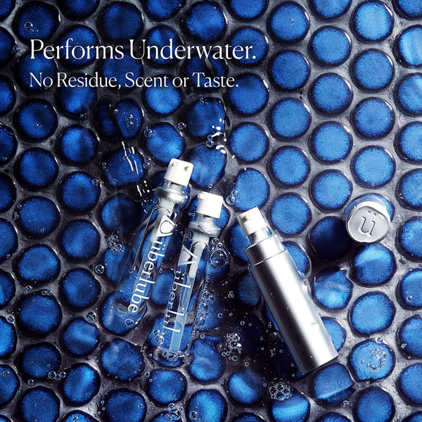 Two clear "liberlube" bottles and one silver pump bottle are submerged in water with blue circular tiles. The text highlights that the product "Performs Underwater. No Residue, Scent or Taste," suggesting its use as a personal lubricant available from Worldcondoms.