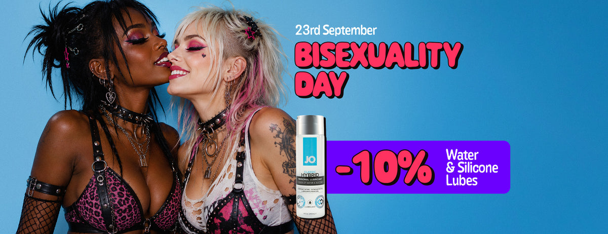 Promotional poster for Bisexuality Day, 23rd September. Two women in colorful alternative-style outfits and makeup pose closely together against a blue background, smiling with their faces touching. A purple promotional banner advertises “-10% Water & Silicone Lubes”, alongside an image of a personal lubricant bottle.